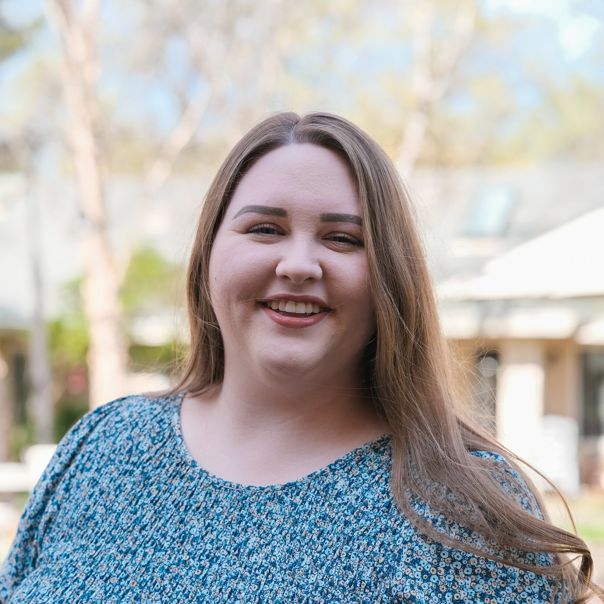 someone smiling in front of a courtyard setting